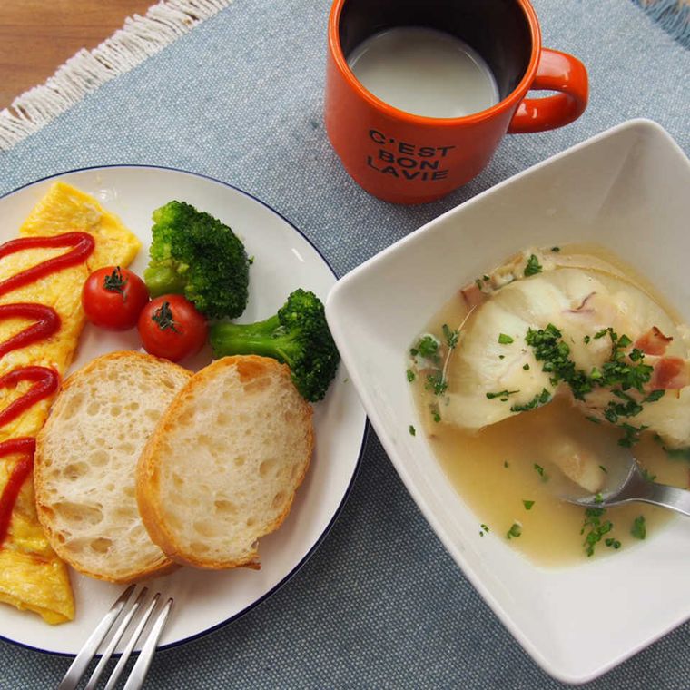 白い四角い器に盛った丸ごと玉ねぎのコンソメスープ