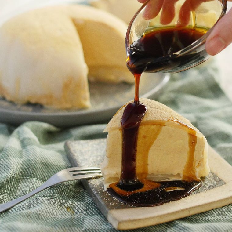 三角のケーキ型に切り分けたアイスクリーム大福に黒蜜をかけている様子