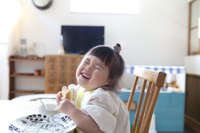 パンを食べながら笑っている子供の様子