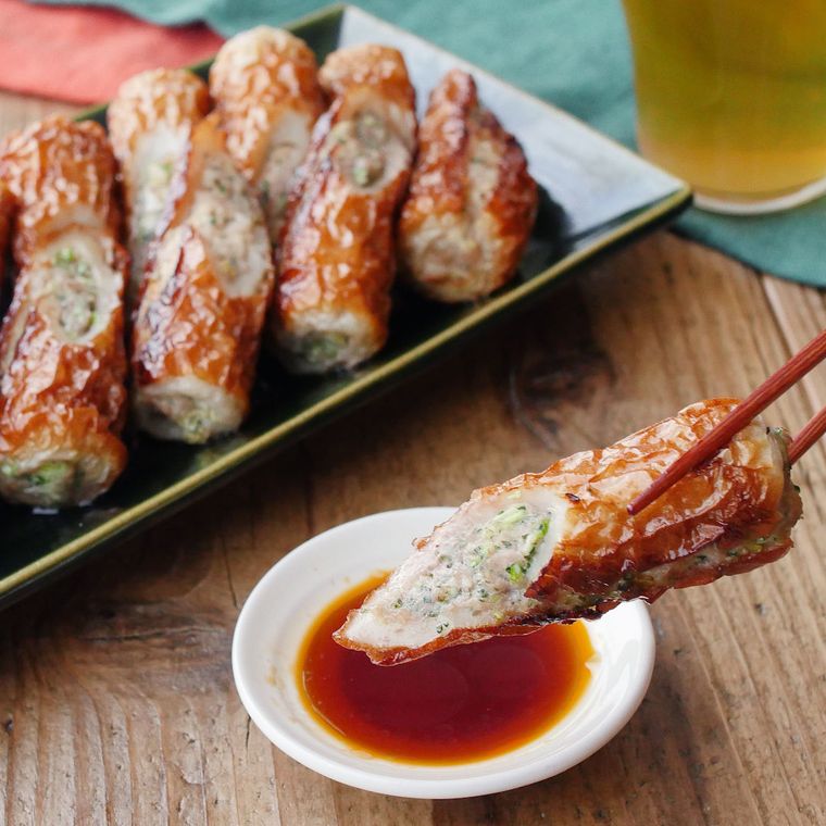 箸でつかんだ青しそのちくわ餃子を、タレにつけている様子