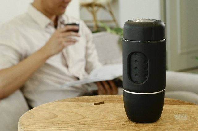 本格エスプレッソメーカー「STARESSO MINI」がテーブルに置かれていて、奥で男性がコーヒーを飲んでいる