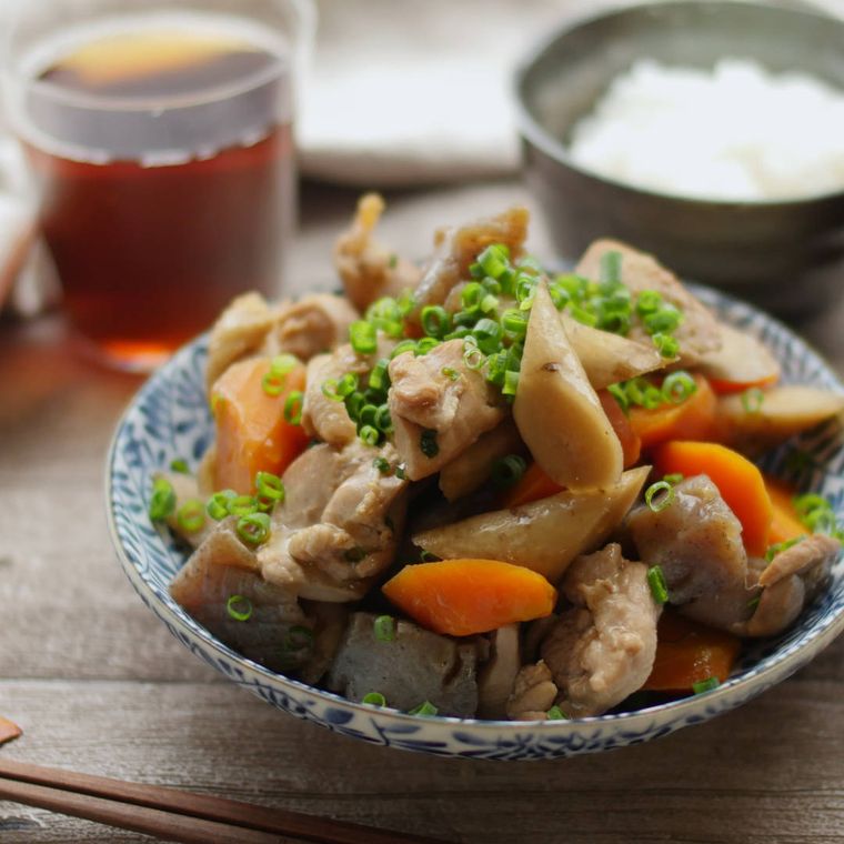 白の青い模様の皿に盛りつけられた鶏肉とごぼうのうま煮