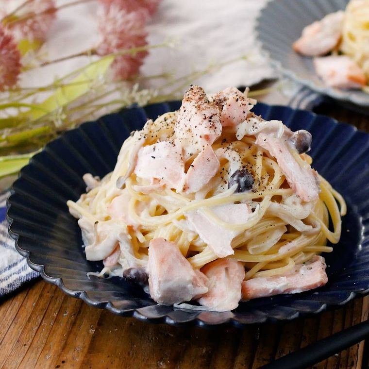 青い花形の皿に盛りつけられたサーモンときのこの和風クリームパスタ