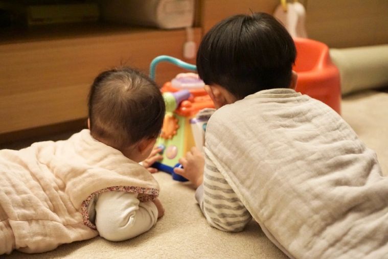 赤ちゃんと男の子がおもちゃで遊んでいる後ろ姿