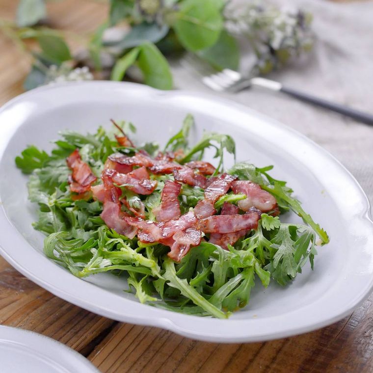 白い皿に春菊とベーコンのサラダが盛られている様子