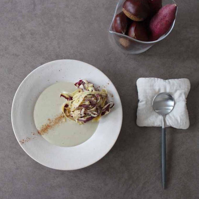 白いスープ皿み盛り付けた栗とさつまいものポタージュに、スプーンが添えられている様子