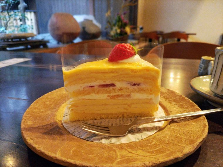 カスタードクリームや生クリームが挟まれたイチゴをのせたミルクレープ