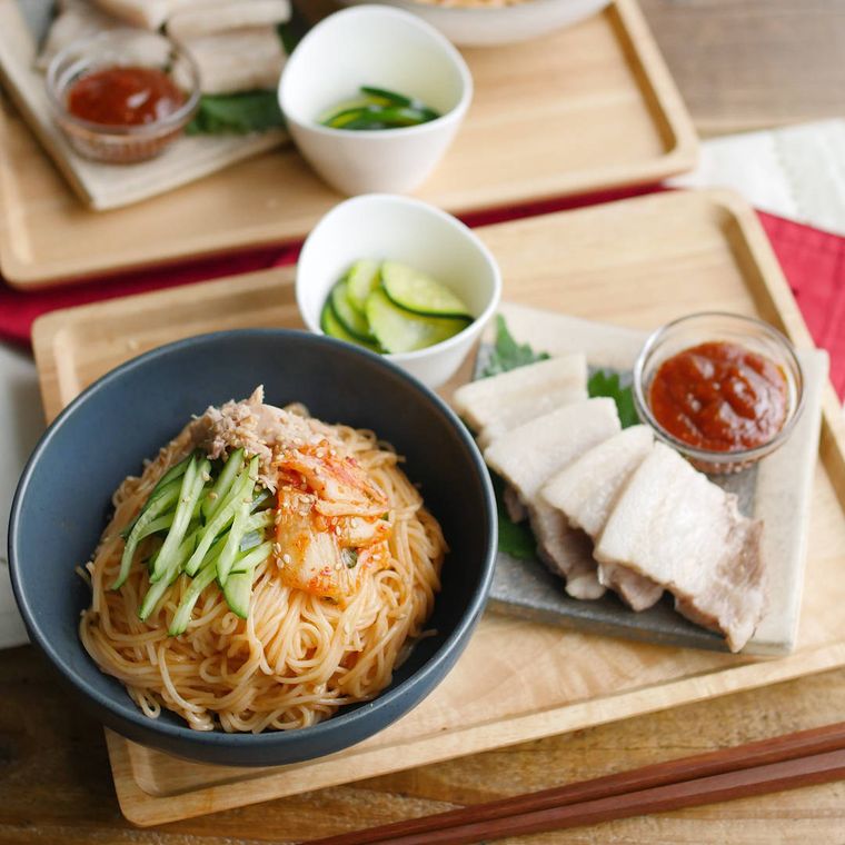 木のお盆に並べたビビンそうめんとズッキーニのナムル、ポッサム風ゆで豚