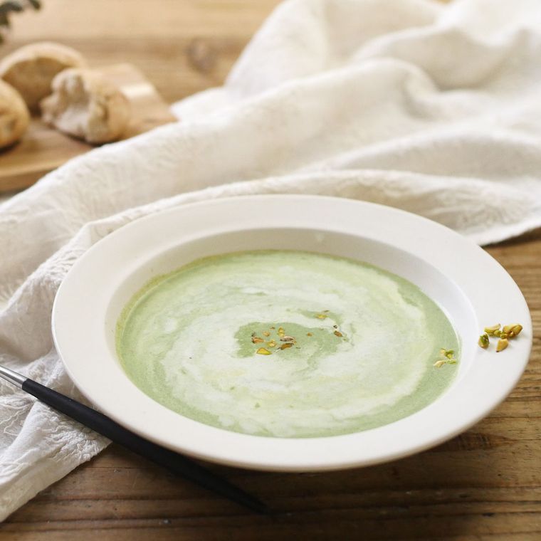 白い皿に盛られている緑色のポタージュ