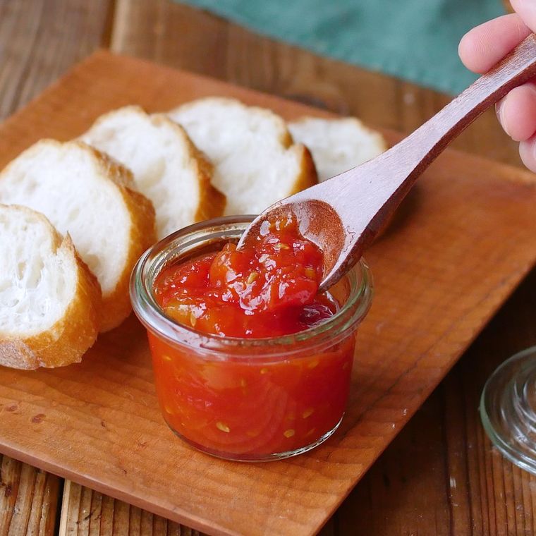 ガラスの保存容器に入ったトマトジャムをスプーンですくっている