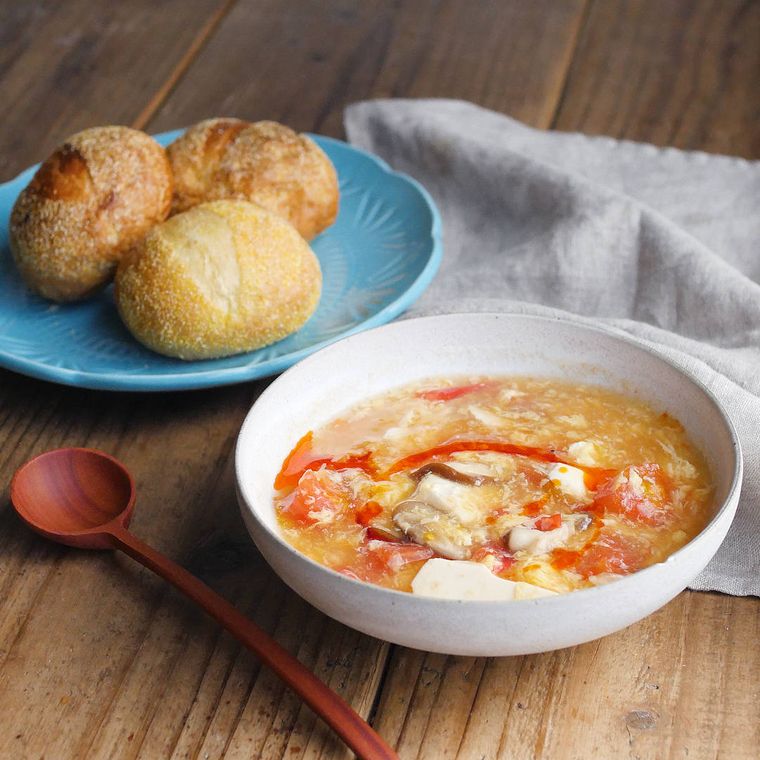 丸いパンを添えた、トマトと豆腐の酸辣湯スープ