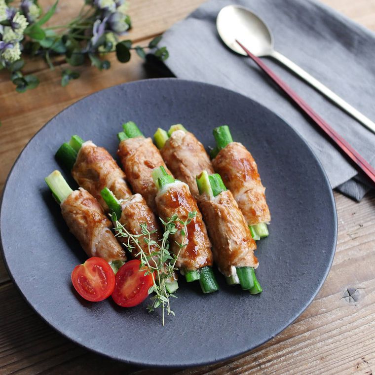 黒い丸皿に盛り付けた、きゅうりの豚肉巻き