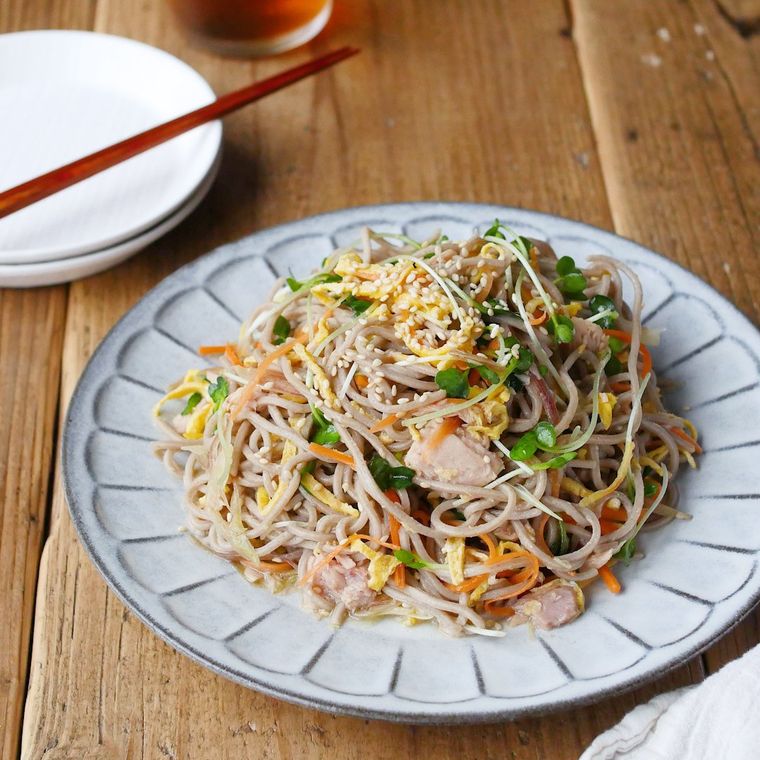 グレーの器に盛った中華風そばサラダが木の机の上に置いてある