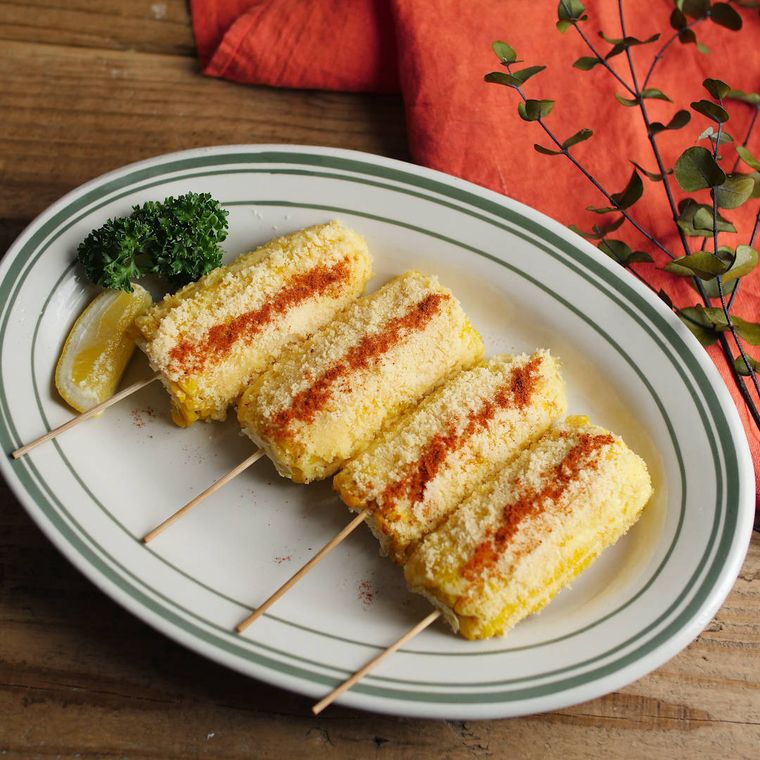 緑色の縁取りが入った楕円の皿に盛られた、メキシカングリルドコーン