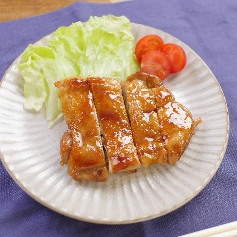 白い皿の上にのった鶏の照り焼きとレタスとトマト