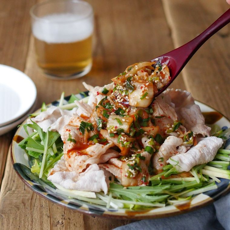 皿の上に水菜や豚肉が盛られていて旨辛ダレをかけている様子