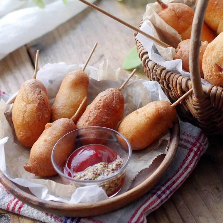 赤のチェック模様のナフキンの上にある木製の皿に置かれている簡単アメリカンドッグ