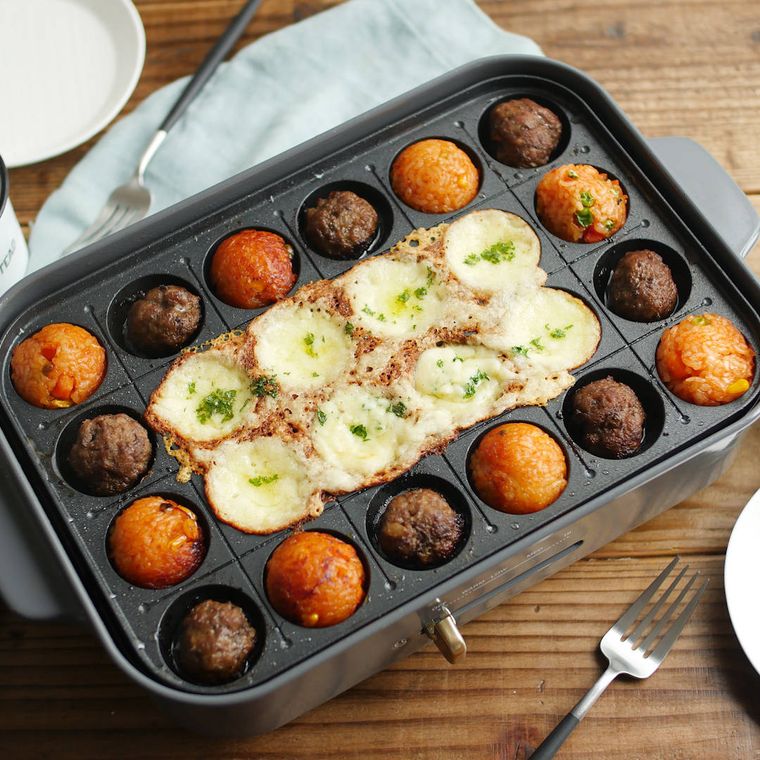 チーズフォンデュを作ったたこ焼き器に、フォークと取り皿が添えられている様子