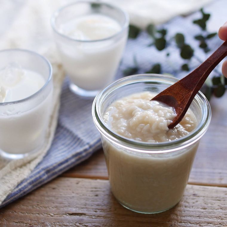 透明な容器に入った甘酒を木のスプーンですくっている