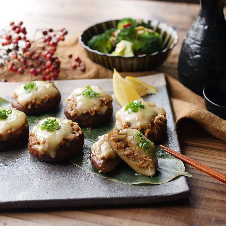 皿に並んだしいたけのさば味噌チーズ焼きと、テーブルに置かれたお酒