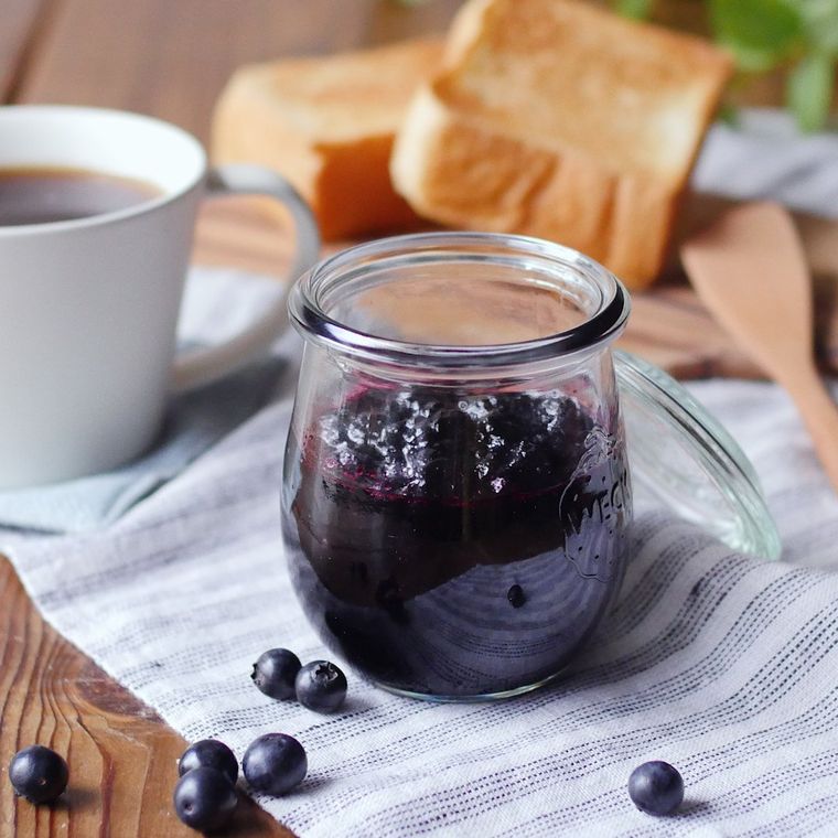 キッチンクロスの上にある瓶にブルーベリージャムが入っている