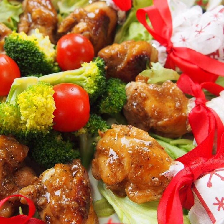 紙ナプキンと赤いリボンで飾られている手羽元の照り焼き