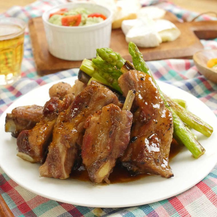 白い丸皿に盛り付けらえているスペアリブとアスパラの甘辛煮