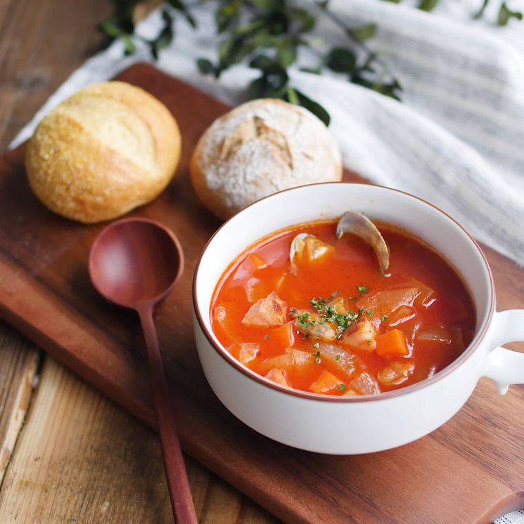 白いスープマグに入ったマンハッタンクラムチャウダーと隣に添えられている丸いパン