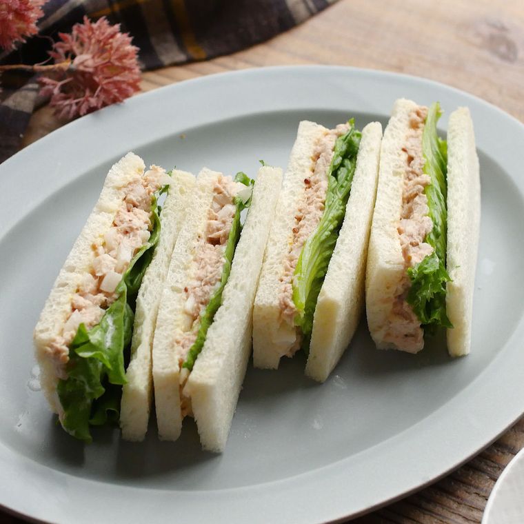 ツナサンドイッチが白い皿に盛り付けられているところ