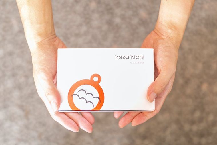 白い箱に入った「kesa kichi」の ディップまんを両手でとっている