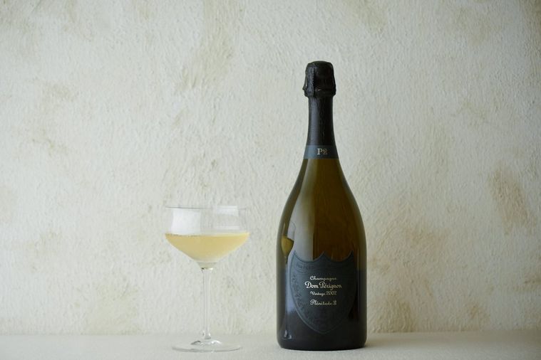 ドン ペリニヨンの瓶とワイングラスに入ったワインが白い背景に置かれている