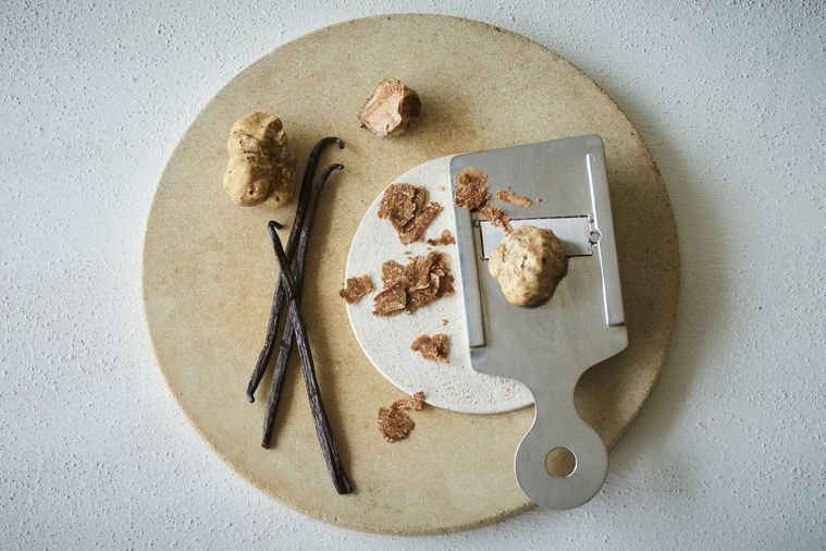 丸い木のおさらに白トリュフが乗ってテーブルに置かれている