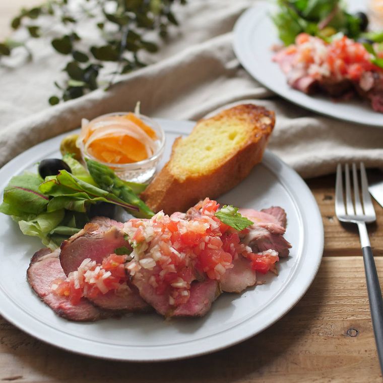 トマトと玉ねぎのソースがかかった、ローストポークがのった白い皿