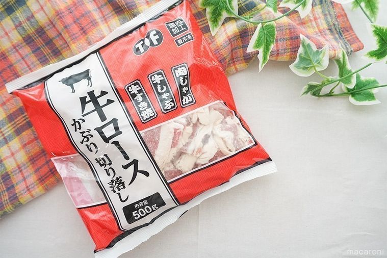 牛ロースかぶり切り落としのパッケージをテーブルに置き、緑の葉とチェック柄の布を添えた様子