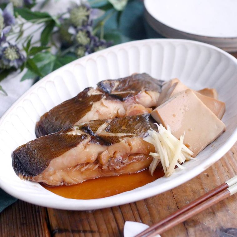 白い皿に盛りつけられたかれい切り身と豆腐の煮付け、針しょうが