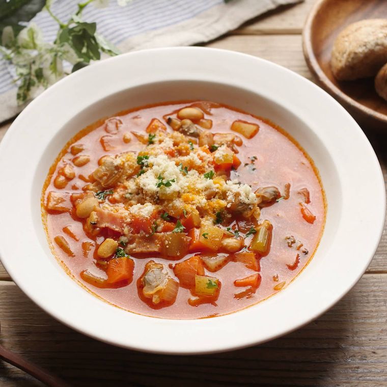 白いスープ皿に盛り付けられているあさりと野菜のトマトスープ