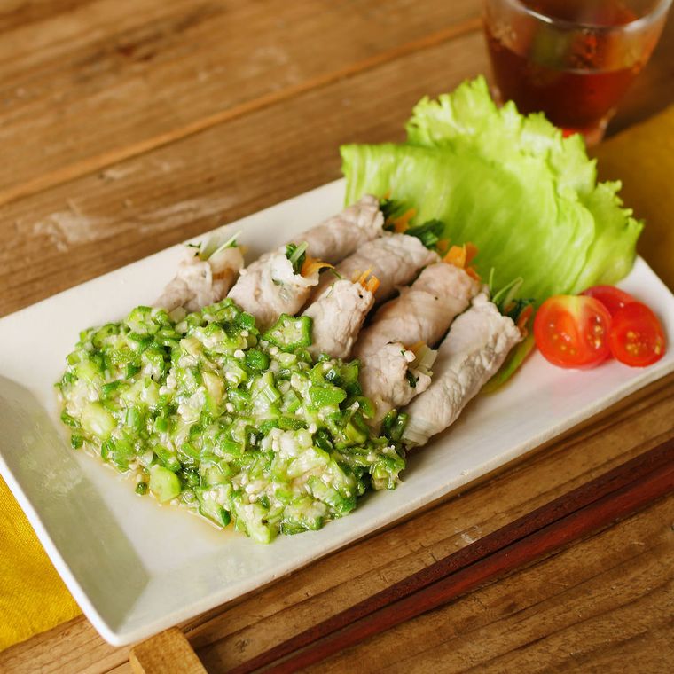 白い四角い皿に盛り付けられているねぎ塩オクラだれの豚しゃぶ野菜巻き