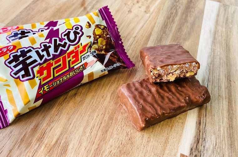 チョコでコーティングされたお菓子、芋けんぴサンダーとパッケージがテーブルの上に置かれている