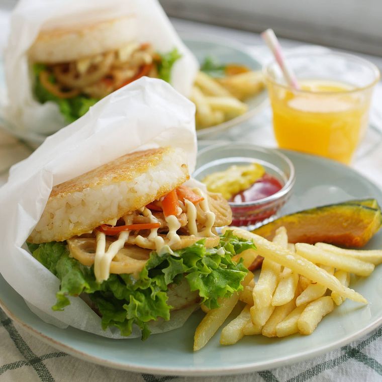 水色の皿に盛り付けられた豚肉とれんこんのライスバーガーとフライドポテト