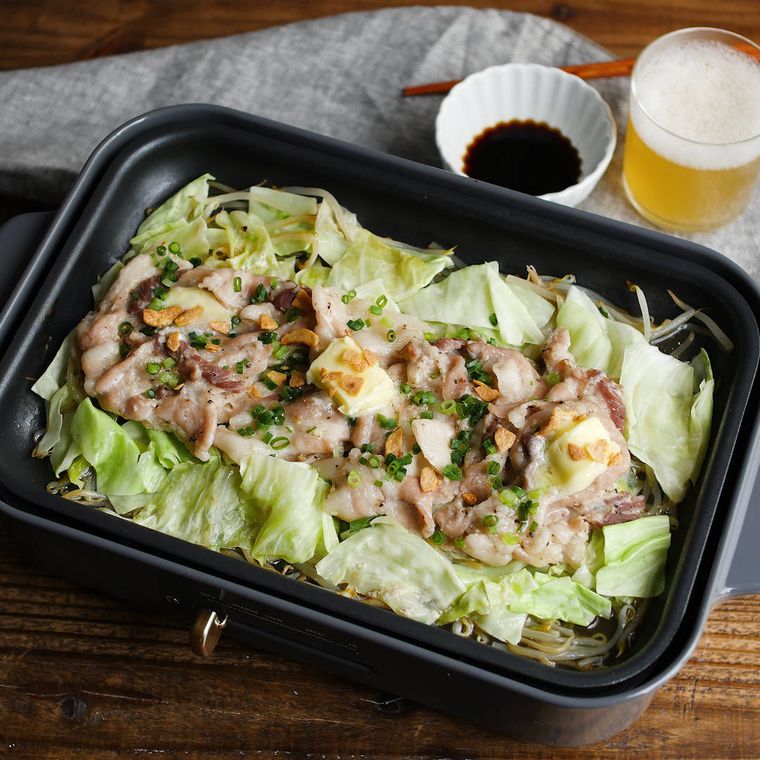 黒いホットプレートでにんにくバターの蒸し豚しゃぶを作る様子