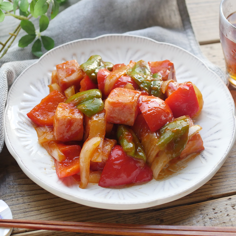 白い皿に入ったベーコンと玉ねぎ、パプリカ、ピーマンの酢豚風