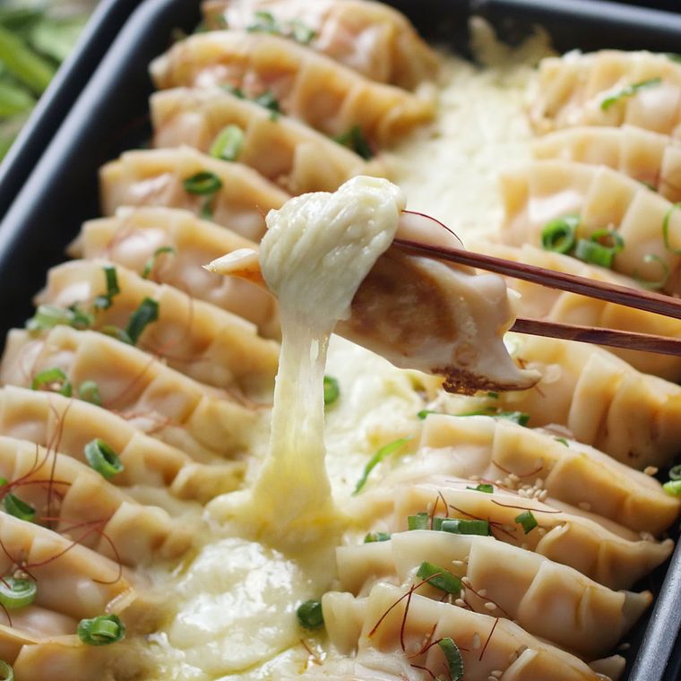 ホットプレートで焼いた餃子をチーズにからめている様子