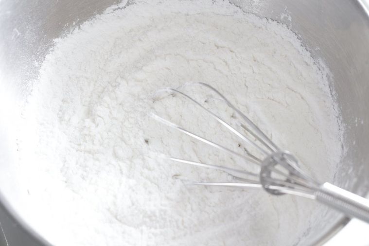 粉が入ったボウルを泡だて器で混ぜている