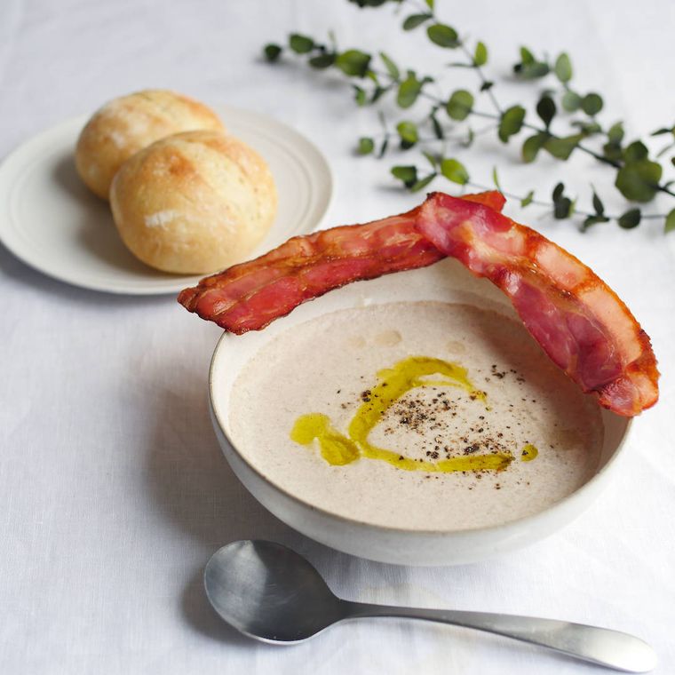 白いスープカップに盛り付けられているブラウンマッシュルームのポタージュ