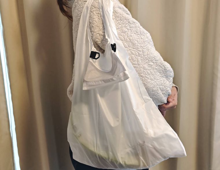 ショルダーになる折りたたみショッピングバッグをかけている様子