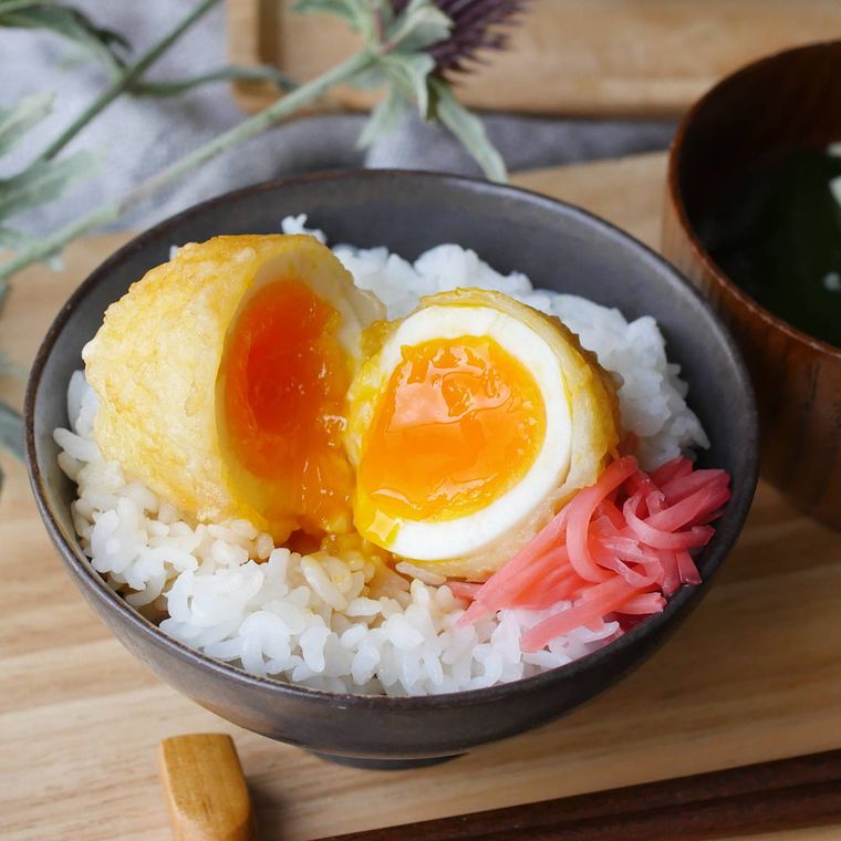 黒い丼に盛りつけられた白いごはんと半熟卵の天ぷら
