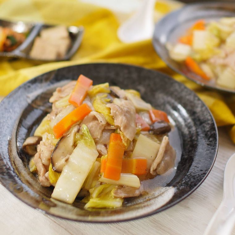 黒い和皿に盛った豚肉の野菜あんかけ