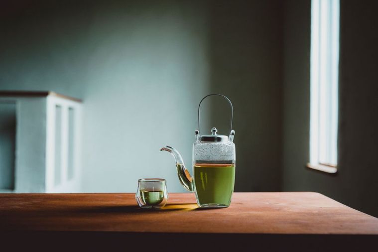 お茶が入った透明の急須と茶碗がテーブルに置かれている