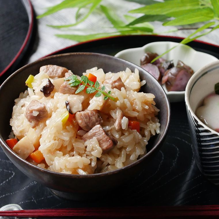 黒い盆の上に、黒い茶碗によそった五目レンジおこわや汁物、小鉢が並んでいる