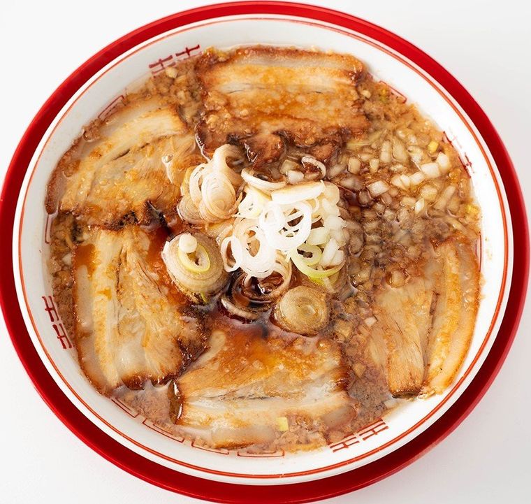 どんぶりの中にねぎとチャーシューが5枚のったラーメンが入って置いてある